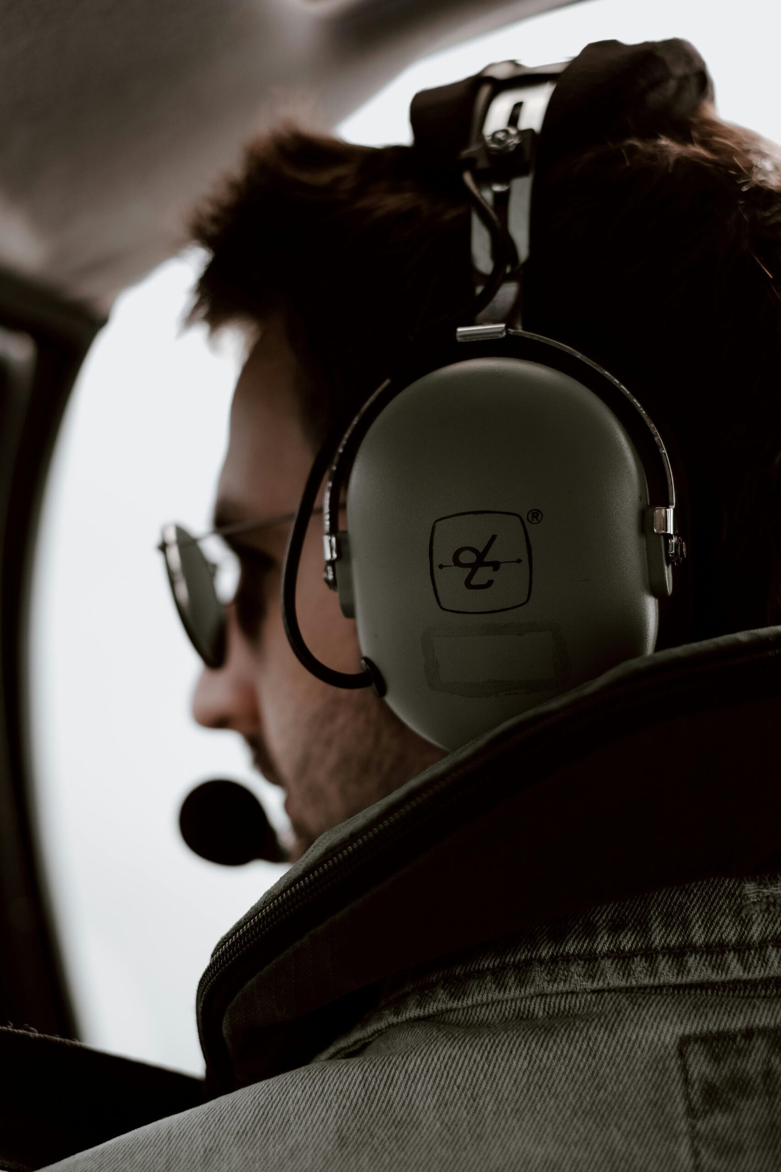 Profile of an aviator in cockpit wearing headset and sunglasses, emphasizing aviation lifestyle.