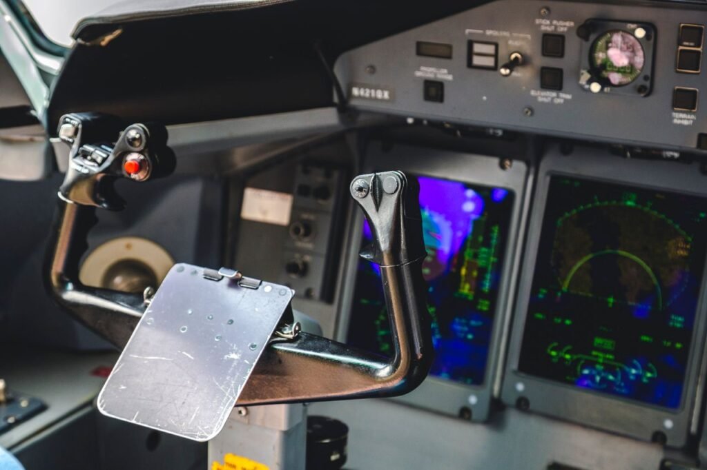 Close-up of aircraft cockpit controls showcasing the yoke and illuminated screens.
