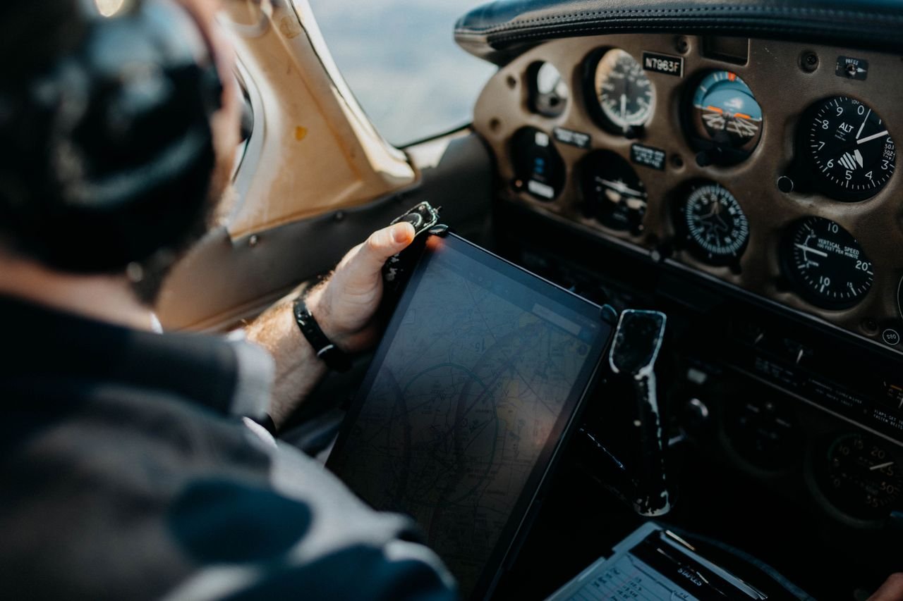 Pilot using tablet for navigation inside an airplane cockpit, showcasing aviation technology.